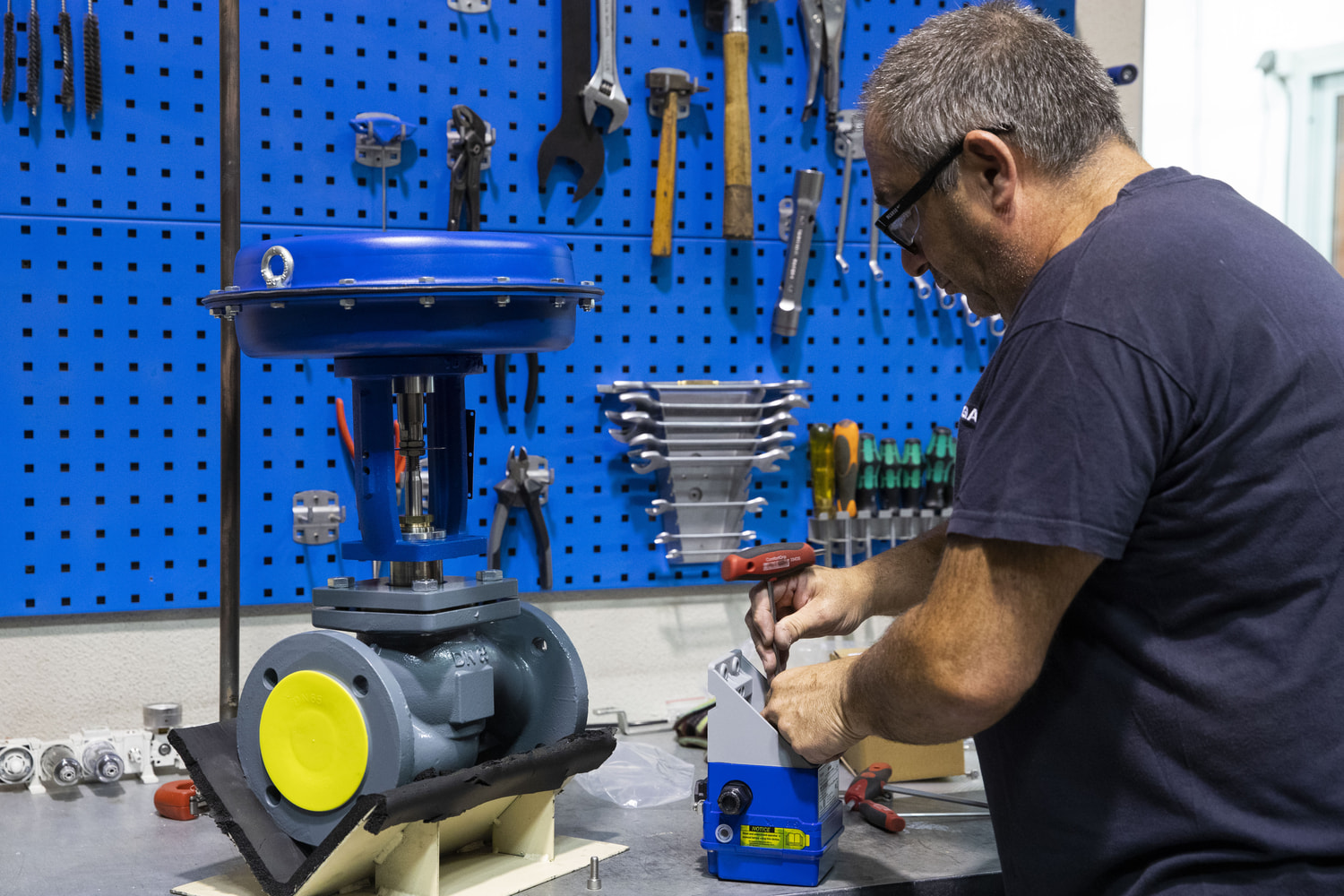 An employee is standing at a work bench and working on a product.